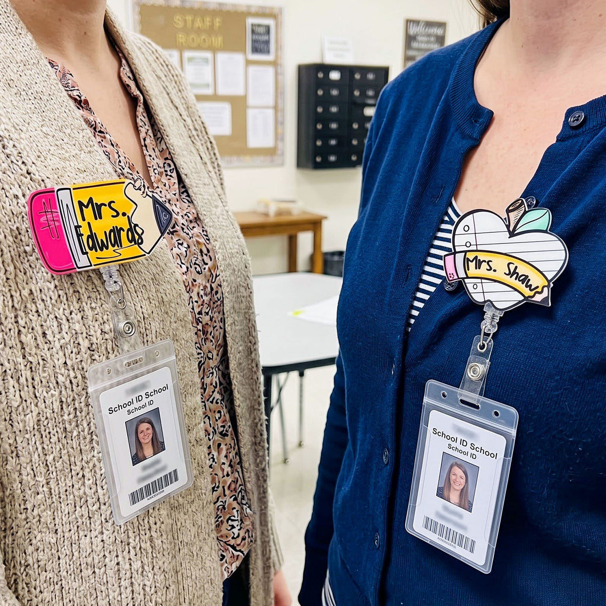 Two women wearing novelty teacher badges and ID badges in a school setting. The badge on the left is yellow with pink and blue accents and reads 'Mrs.