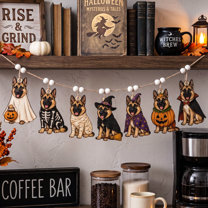 A Halloween-themed garland featuring illustrated German Shepherd dogs in various costumes, hanging on a string in a cozy, styled home setting with autumn decor and books on a shelf.