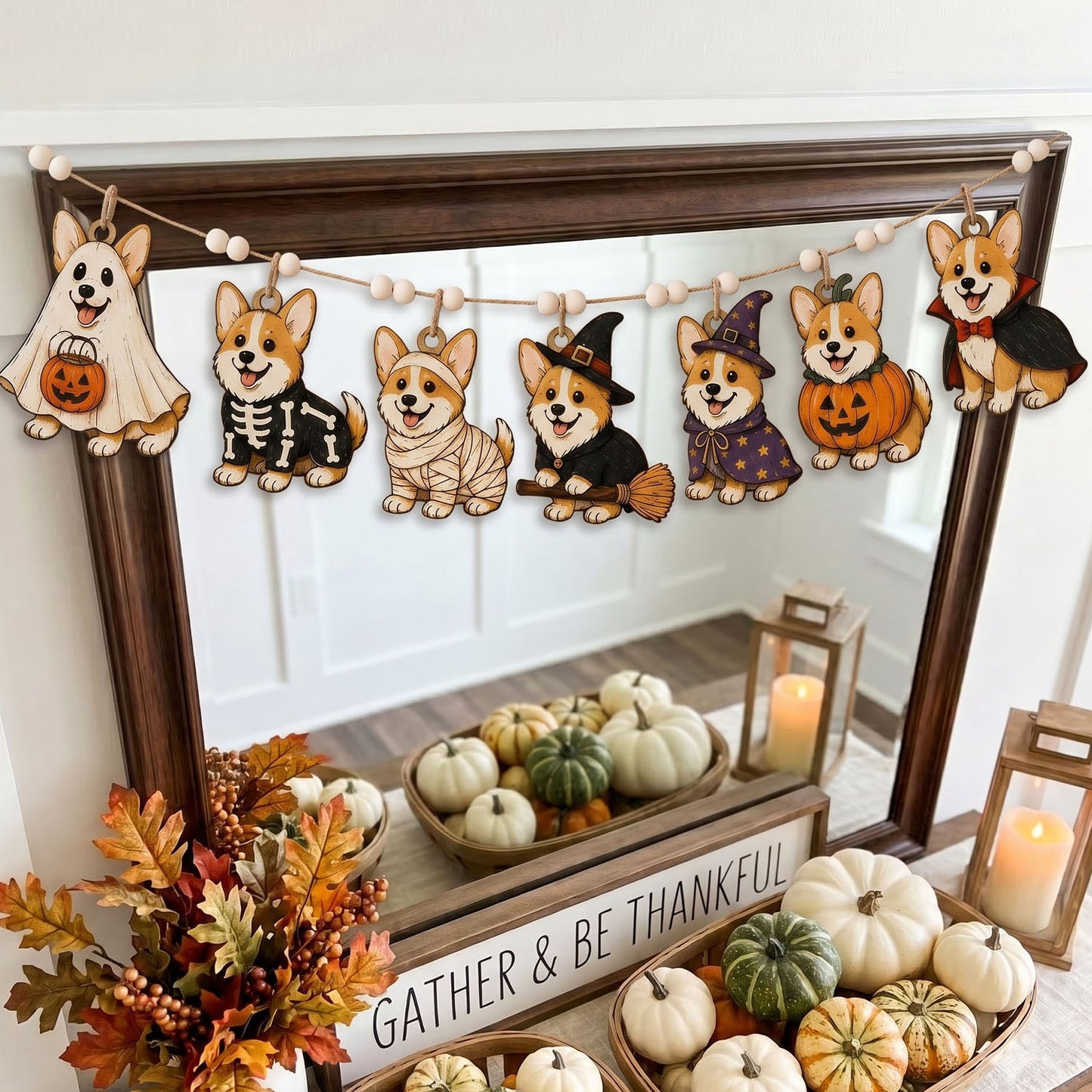 A Halloween-themed wooden dog garland with seven cutout dogs dressed in ghost, skeleton, bandage, witch, wizard, pumpkin, and vampire costumes, hanging across a dark wood mirror in a decorated fall display with pumpkins and candles.