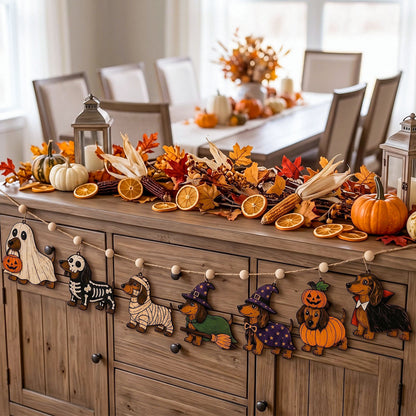 A styled autumn dining room scene with a wooden sideboard covered in fall decorations, including pumpkins, corn, dried leaves, orange slices, lanterns, and a string of wooden dog cutouts dressed as ghosts, zebra, mummy, witch, and pumpkin.